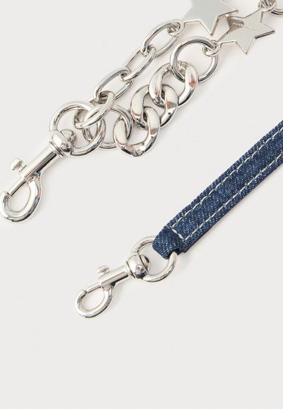 Strieborný kovový retiazka s oválnymi očkami a hviezdičkovými ozdobami, spojená s tmavým riflovým remienkom, oba s otočnými karabínami.