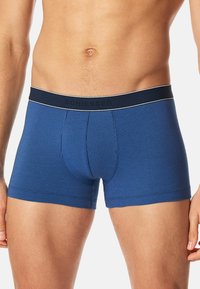 Modré boxerky s ribbed texturou a přiléhavým střihem. Obsahují značkový pas v tmavě modré barvě s bílými akcentními stehy.