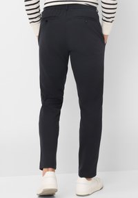 Marineblauwe broek in een slim fit ontwerp, met een elastische tailleband, achterzakken met knoopsluitingen en een gladde stofstructuur.