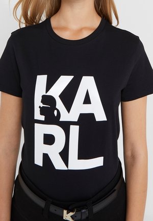Black t-shirt with large white "KARL" letters, featuring a white silhouette of a face with ponytail and sunglasses inside the "K" letter.