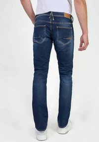 Jeans de mezclilla azul oscuro con corte slim, que cuentan con bolsillos traseros y un acento de cuero en la cinturilla. Terminados con una sutil textura deslavada.