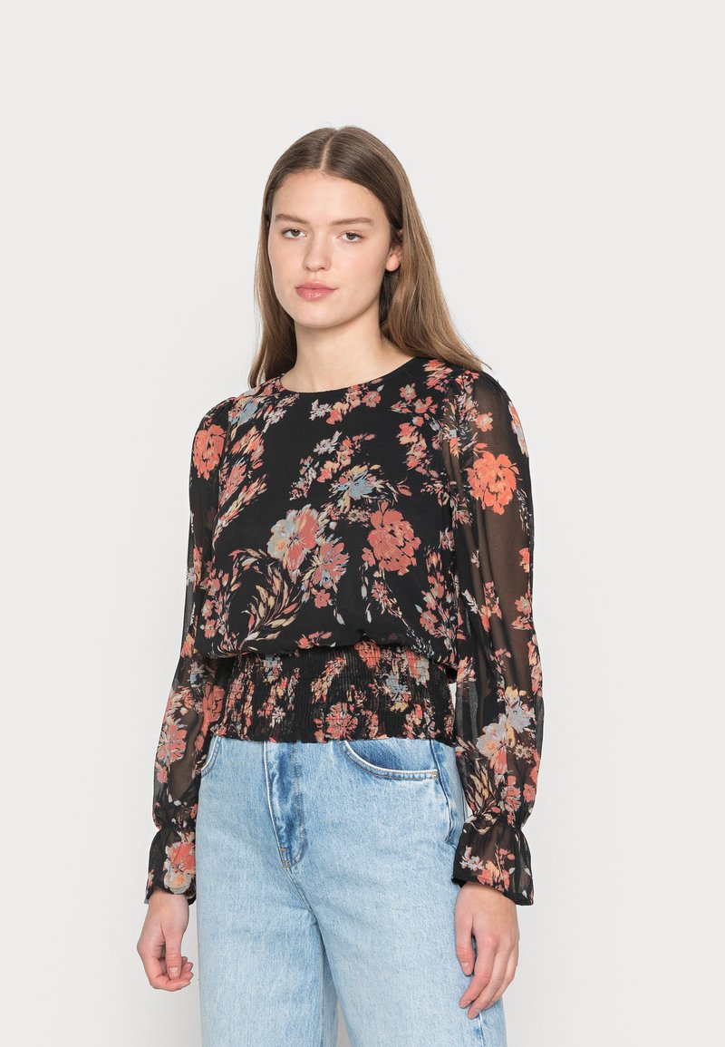 Blusa preta floral com mangas longas, apresentando uma cintura franzida e tecido transparente. Flores em vermelho, laranja e azul contra um fundo escuro.