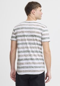 Striped t-shirt featuring alternating green, brown, and white horizontal lines; casual, soft fabric; round neck; short sleeves.