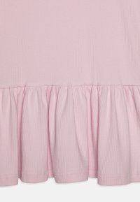 Rosa ribbet stoff med volangkant. Teksturen er myk og glatt, med jevnt fordelte vertikale linjer og en uformell design.
