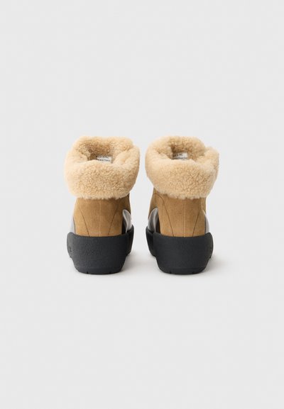 Botas de tobillo de ante marrón con un lujoso cuello de borreguito color crema, suela de goma y detalles de costura únicos en los lados.