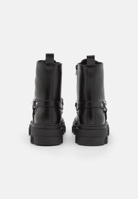 Svarta läderankelstövlar med en kraftig sula, utrustade med en siddragkedja, remdetalj och förstärkt häl. Matt yta och slank siluett.