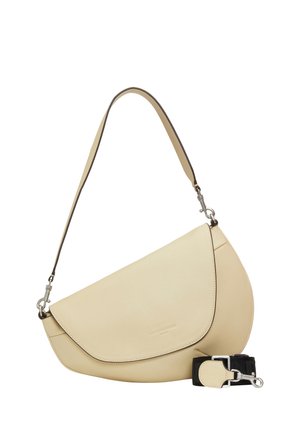 Beige schultertasche in halbmondform mit geschwungener klappe und abnehmbarem schwarzem riemen mit silberfarbenen beschlägen auf weißem hintergrund.