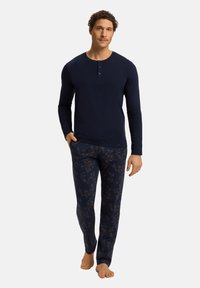 Navy lange mouwen henley-shirt met een drieknopensluiting. Bijpassende pyjamabroek met een donker bloemenpatroon op een marineblauwe achtergrond.