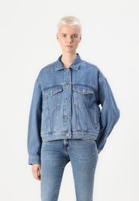 Giacca di jeans azzurro chiaro con vestibilità rilassata, caratterizzata da colletto a contrasto, due tasche sul petto e chiusura a bottoni. Aspetto testurizzato, leggermente sbiadito.