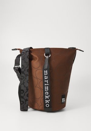 Bruine cilindrische schoudertas met subtiel bloemenpatroon, zwarte verstelbare riem en verticale zwarte riem met het label "marimekko".