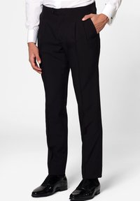 Black tailored trousers with a flat front, subtle pleats, and side pockets, made from smooth fabric. Paired with polished black dress shoes.
