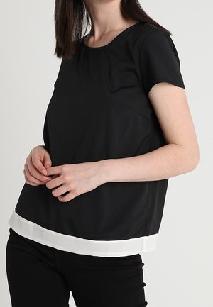 Top nero a maniche corte con scollatura rotonda, caratterizzato da un orlo bianco e una texture morbida. Design semplice, senza motivi o accenti visibili.