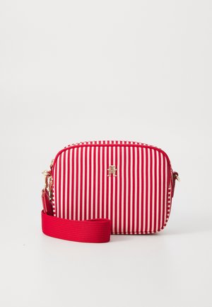 Rød- og hvidstribet rektangulær crossbodytaske med guld logoemblem og bred rød justerbar skulderrem.