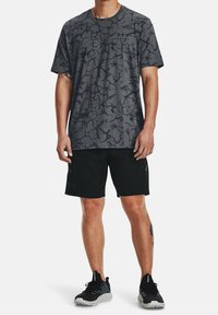 Grå kortärmad t-shirt med ett subtilt sprucket mönster, tillsammans med svarta shorts och grå träningsskor. Enkel och funktionell design.