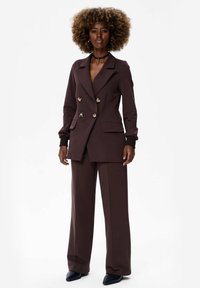 Bordeaux dubbelzijdig blazer met gouden knopen, gecombineerd met bijpassende wijde broek. De stof heeft een gladde textuur en een gestructureerd ontwerp.
