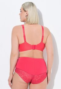 Růžová podprsenka a kalhotky s vysokým pasem. Podprsenka má nastavitelné ramínka a háčkové zapínání. Na kalhotkách jsou krajkové detaily. Matný a texturovaný povrch.