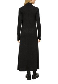 Robe noire à manches longues avec un col haut et une silhouette fluide. Fabriquée en tissu texturé avec de subtils éclats métalliques.