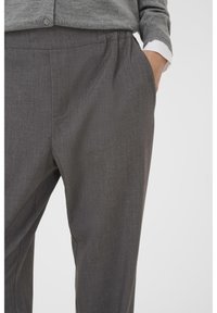 Pantalons gris ajustés avec une texture douce, dotés de poches latérales et d'une coupe décontractée. Taille élastique pour le confort et la facilité de port.
