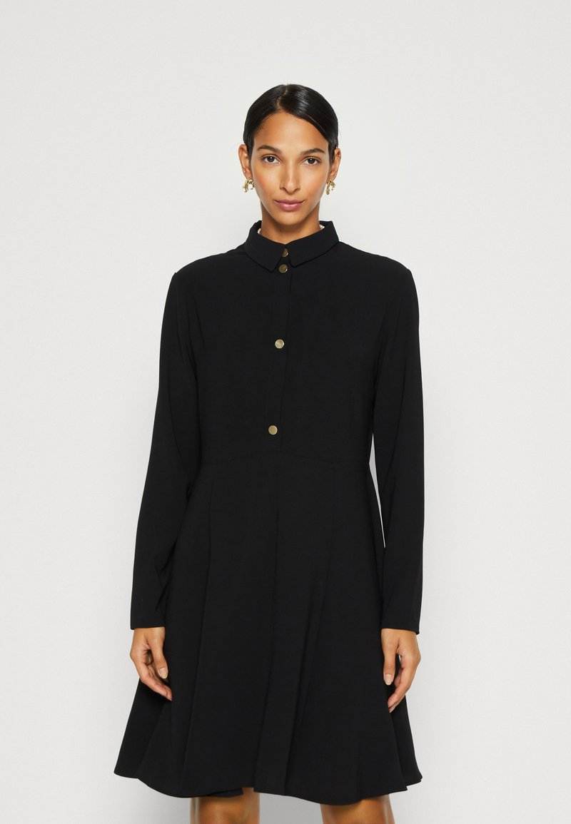 Schwarzes Kleid mit Kragen, langen Ärmeln und schwingendem Rock. Verfügt über goldene Knöpfe auf der Vorderseite und eine glatte Stoffstruktur.