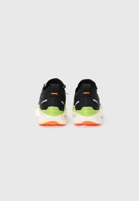 Pair of black sneakers with green heel accents, orange highlights, and white soles shown from the back on a plain light background.