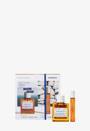 Korres Avgoustos Eau de Toilette Geschenkset mit 50-ml-Flasche und 10-ml-Spray, bernsteinfarbene Flüssigkeit, neben einer weißen Box mit Bild einer griechischen Steinmauer dargestellt.