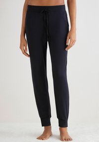 Zwarte joggers gemaakt van zacht materiaal met een elastische tailleband, geribbelde boorden en zijzakken. Ontworpen voor comfort en bewegingsvrijheid.