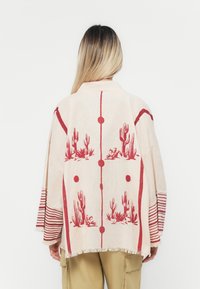 Svijetlosmeđi kimono s crvenim motivom kaktusa, s dugim rukavima sa prugastim detaljima i resicama na rubovima. Opušteni kroj.