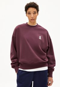 Burgunderfarbener Oversize-Sweatshirt mit Rundhalsausschnitt, das ein kleines graues Ribbons-Logo auf der Brust und gerippte Bündchen aufweist. Weiche Stoffstruktur.