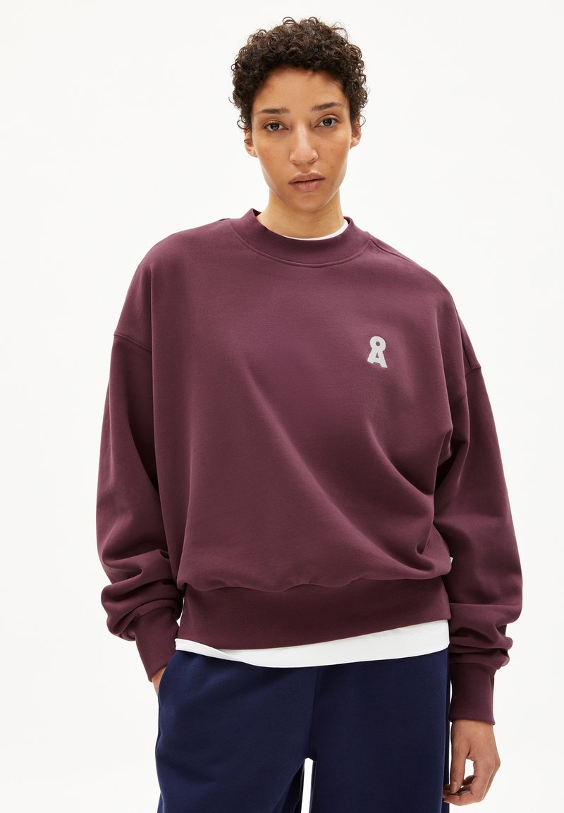 Burgunderfarbener Oversize-Sweatshirt mit Rundhalsausschnitt, das ein kleines graues Ribbons-Logo auf der Brust und gerippte Bündchen aufweist. Weiche Stoffstruktur.
