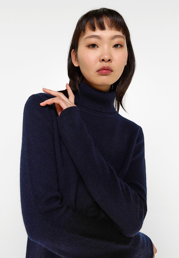 Dunkelblauer Rollkragenpullover aus weichem Strickmaterial, mit langen Ärmeln und lockerer Passform, mit geripptem Halsausschnitt und Bündchen.