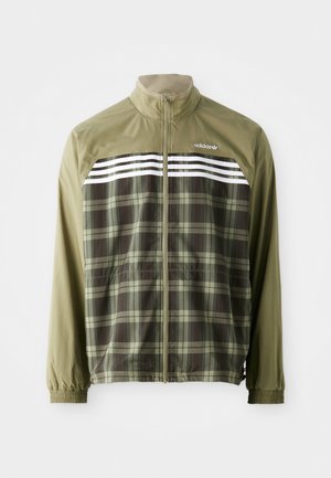 Chaqueta cortavientos de cuadros verdes con cremallera frontal, puños elásticos y rayas blancas en el pecho. Tejido de poliéster, diseño ligero.