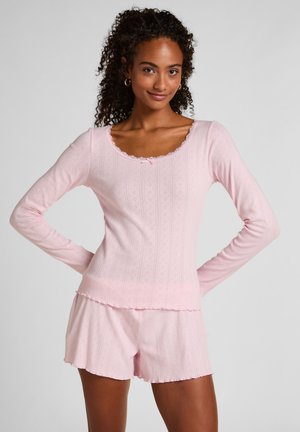 Lichtroze set bestaande uit een top met lange mouwen en korte broek, gemaakt van een gestructureerde stof. De top heeft een getand halslijn en korte mouwen met een delicaat patroon.