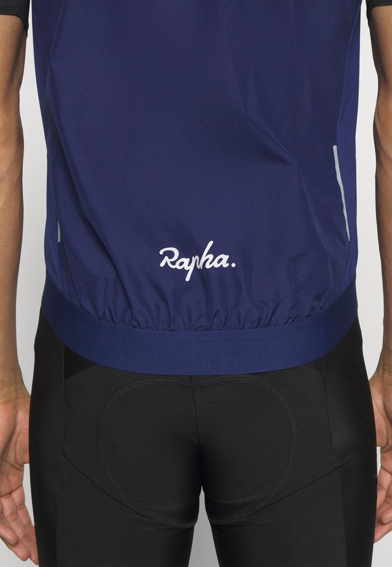 Marineblauwe Rapha fietsjersey met elastische zoom en reflecterende details, gecombineerd met zwarte gevoerde fietsshorts. Zacht, lichtgewicht materiaal.