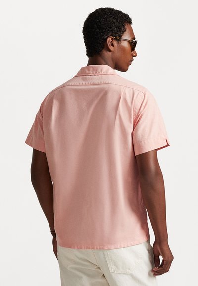 Κοντομάνικο πουκάμισο από ανοιχτό ροζ βαμβακερό ύφασμα, με ίσια γραμμή, διακριτική υφή και κλασικό γιακά. Ξεχωριστή ραφή με κουμπιά στο πίσω μέρος.