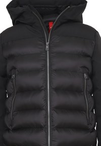 Giubbotto imbottito nero con cappuccio, caratterizzato da un design trapuntato, chiusura con zip frontale e tasche laterali. Tessuto liscio e leggermente lucido.