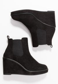 Bottines à talon noir en daim doux avec des côtés élastiques et une semelle en caoutchouc texturé. Dotées d'une languette pour un enfilage facile.