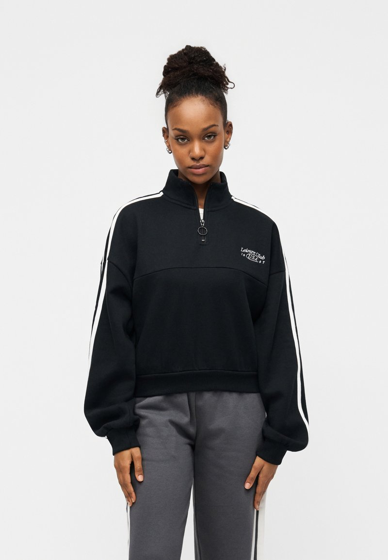 Μαύρο φούτερ με φερμουάρ, λευκές λωρίδες στα πλαϊνά, ριμπ τελείωμα και κεντημένο λογότυπο στο στήθος. Κατασκευασμένο από απαλό ύφασμα, με άνετη εφαρμογή.