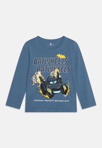 Niebieska koszulka z długim rękawem z motywem kartoonowym samochodu z płomieniami i żółtymi akcentami, z napisem "BATWHEELS" i "MISJA: CHRONIĆ GOTHAM CITY."