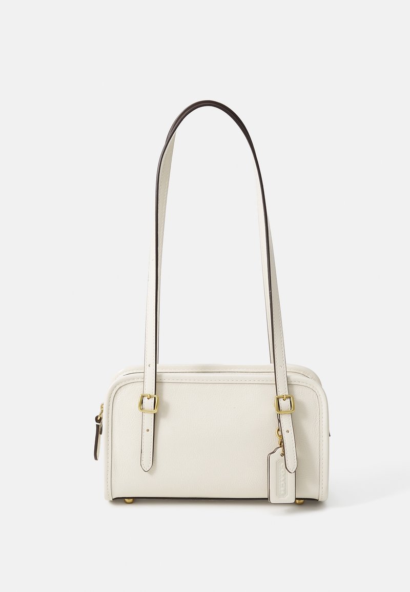 Petit sac à main rectangulaire en cuir ivoire avec longues sangles ajustables, boucles dorées et une étiquette suspendue sur un fond uni.