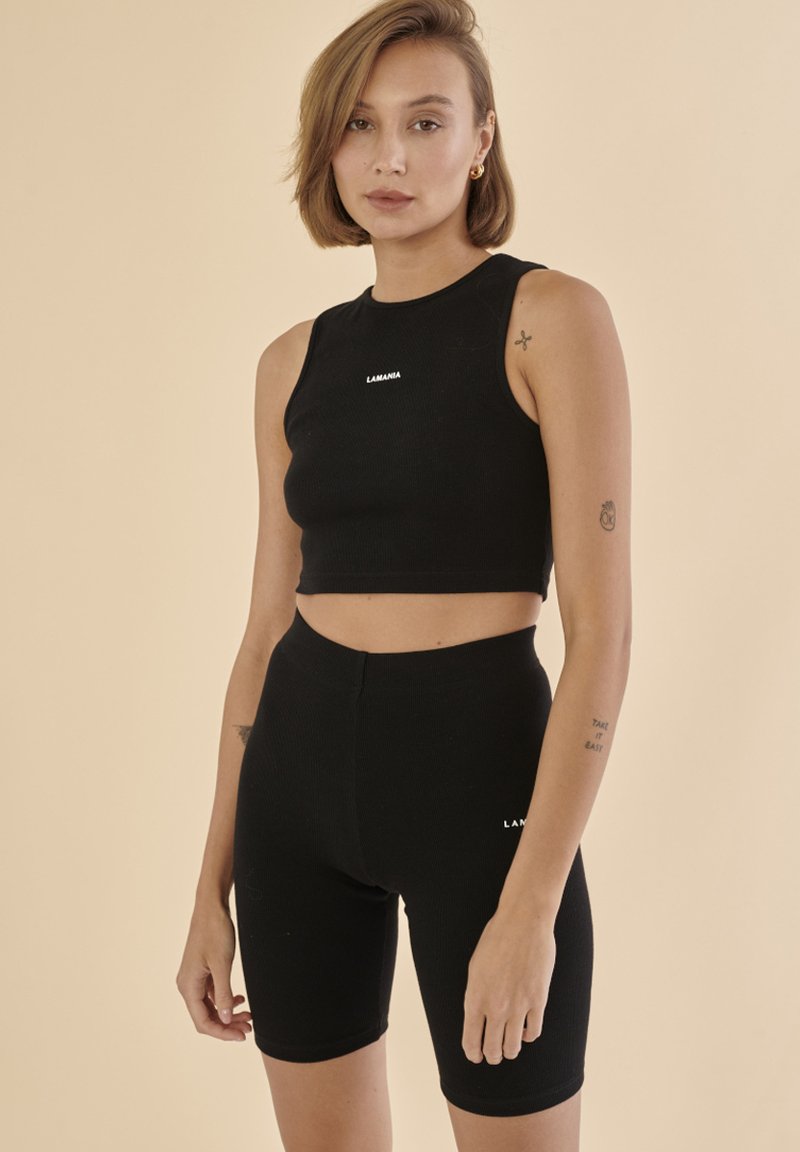 Černý žebrovaný crop top a odpovídající vysoké cyklistické šortky, s malým bílým logem "LAMANA" vpředu. Hladká textura, přiléhavý design.