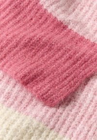Couverture en tricot avec un design rayé en rose pâle et crème. Texture douce en laine, avec des motifs nervurés et des teintes variées de rose.