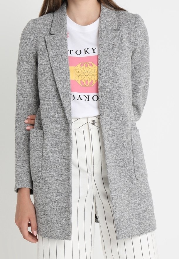 Grijze blazer van een gestructureerde stof, met een enkele knoopsluiting, notch lapels en twee voorzakken, gecombineerd met een graphic t-shirt.