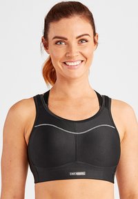 Zwarte sportbeha van een gladde, stretchy stof, met zilveren stiksels en een merklabel aan de voorkant.