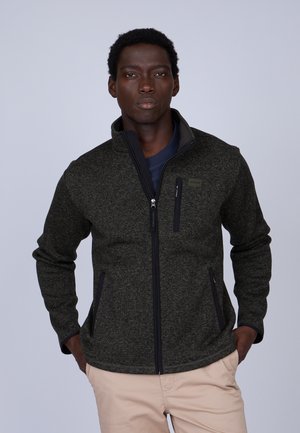 Veste en polaire vert foncé avec un col haut, fermeture éclair à l'avant et accents noirs. Comprend deux poches latérales et une poche poitrine zippée.