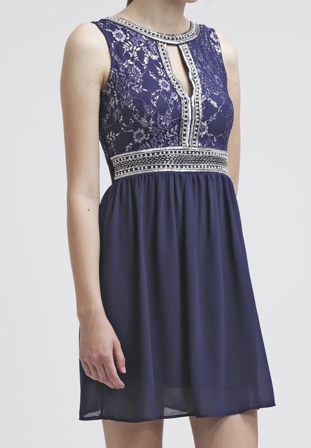 Robe bleu marine avec corsage en dentelle, encolure trou de serrure et taille ornée de perles ; jupe fluide ; design sans manches. Tissu doux et texturé.