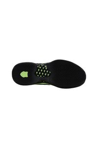 Suela de zapato deportivo negro con acentos verdes. Presenta una superficie de goma texturizada y un patrón de onda para mayor tracción. Diseño ligero.