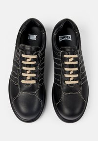 Svarta lädersneakers med beige snörning, med en strukturerad överdel och kontrasterande sömmar. Logotags för "TWINS" och "CAMPER" inuti.