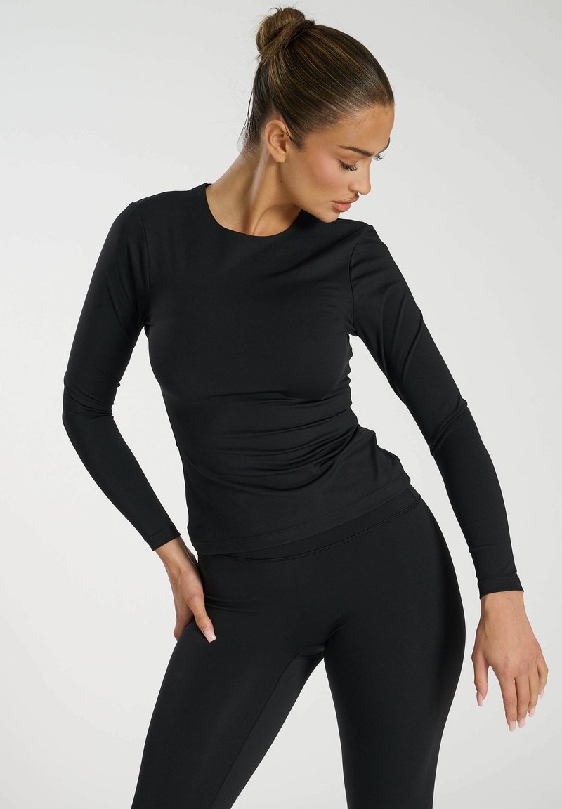Czarna, długosleeve'owa bluzka sportowa z okrągłym dekoltem i dopasowanym krojem. Wykonana z gładkiego, elastycznego materiału, ma marszczenia w okolicy talii.