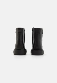Botine negre din piele, cu glezna, cu o textură netedă, fermoare la spate, talpă robustă neagră și design minimalist. Fără marcaj vizibil.