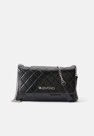 Clutch negro de cuero acolchado con una cadena, que presenta un logo en plata. Forma rectangular, textura brillante y patrón de diamantes.